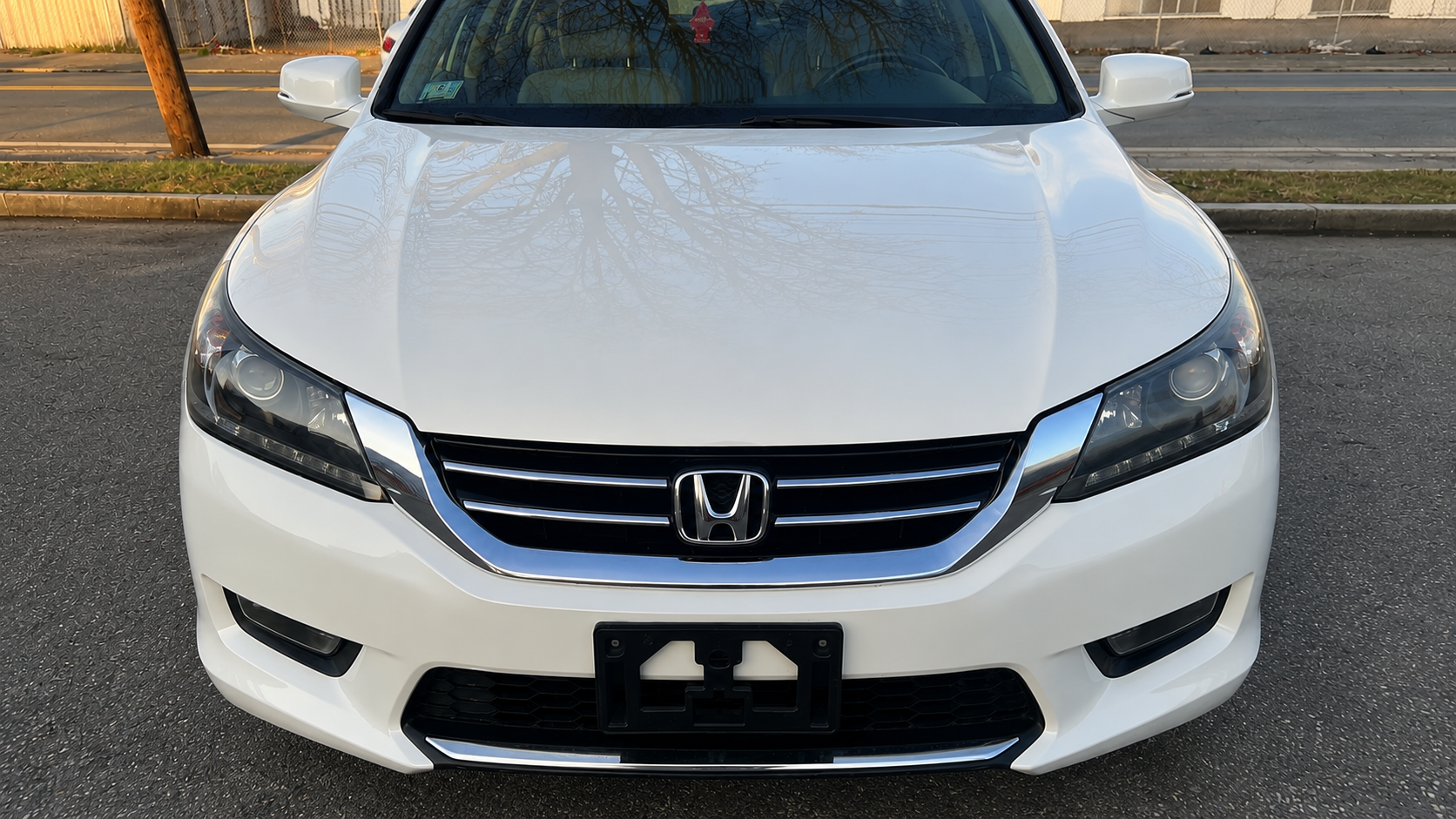 Completed front-end collision repair of a white Honda Accord with restored bumper, chrome grille, headlights and factory-matched white paint at WL Auto Collision in Brockton, Massachusetts.