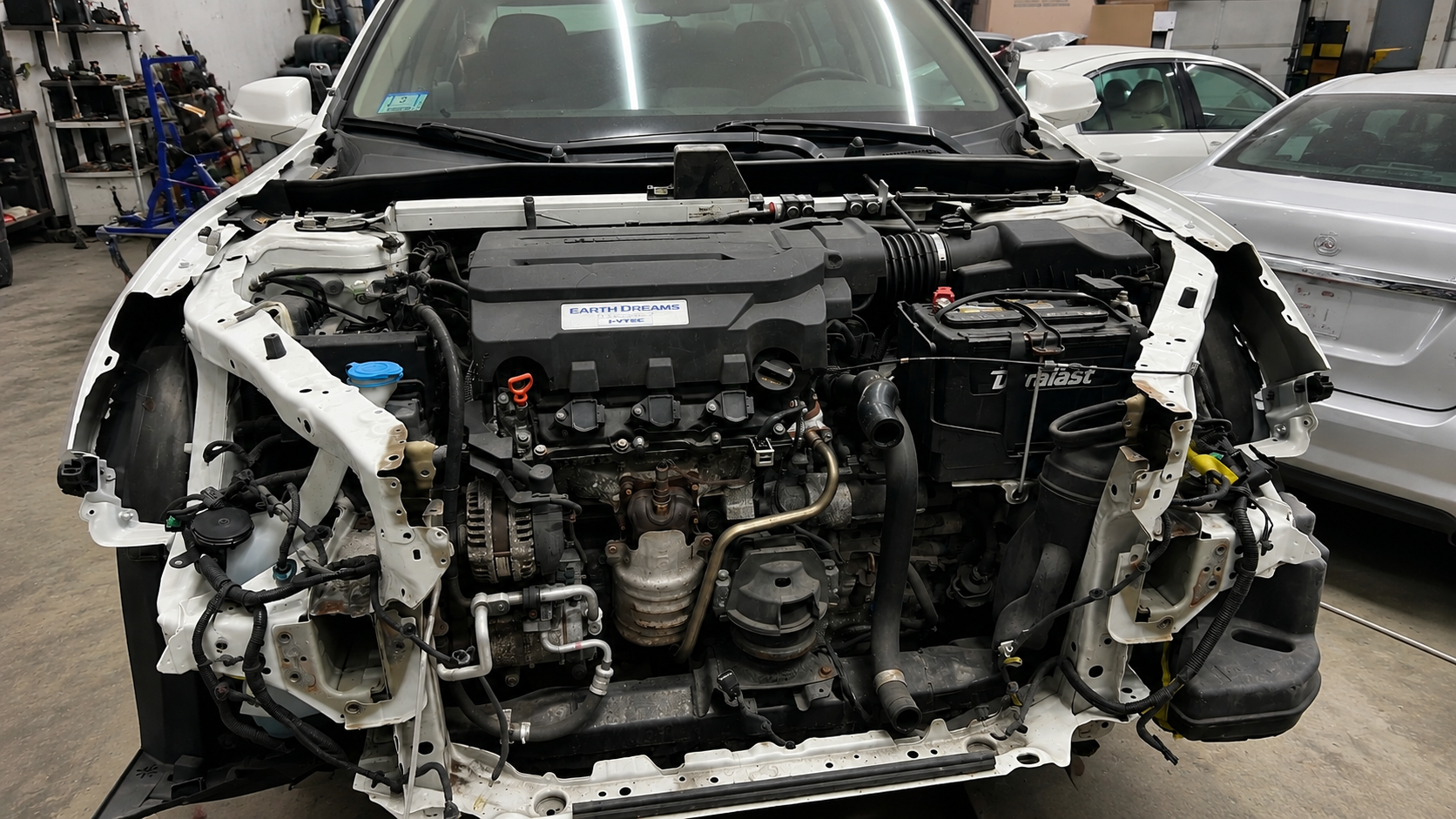 Before front-end collision repair of a white Honda Accord with the front end stripped down to the engine bay, radiator support and wiring harness at WL Auto Collision in Brockton, Massachusetts.