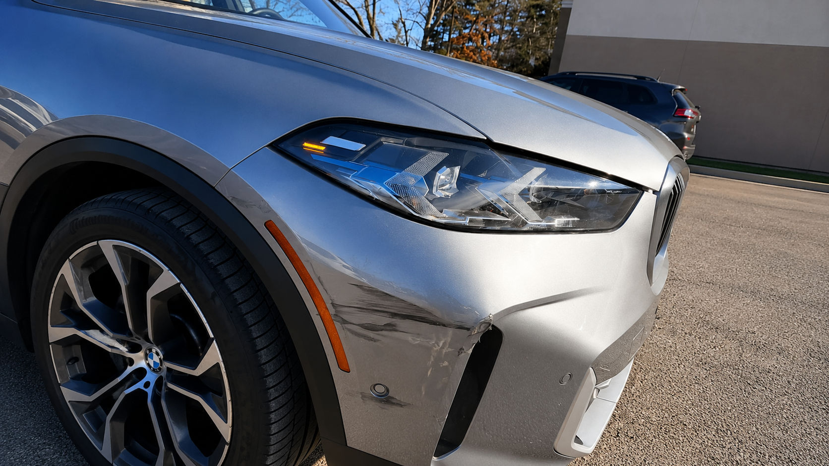 Before front-left bumper and fender repair of a silver BMW X5 showing dented fender and scuffed bumper at WL Auto Collision in Brockton, Massachusetts.